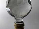 une boule de cristal posée sur un socle en bois, sur fond blanc