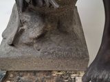 statue of a dog on a pedestal with a bird on it ' s head