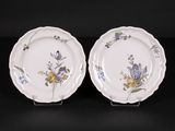 two plates with floral designs on them sitting on a black surface