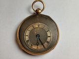 a gold pocket watch with roman numerals on the face