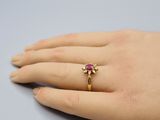 la main de quelqu'un, ornée d'une bague en or sertie d'une pierre rose