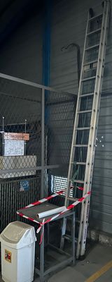 a ladder leaning against the wall next to a trash can and a trash can