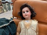 a doll that is sitting on a chair next to a teddy bear