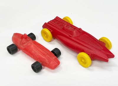 une petite voiture rouge à côté d'une autre petite voiture rouge, posées sur une surface blanche