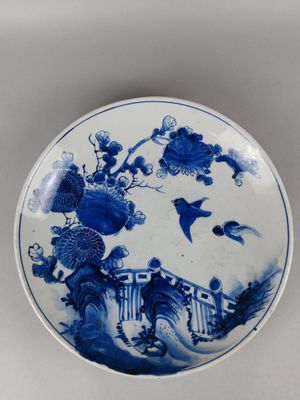 a blue and white plate with a bird and flowers on it