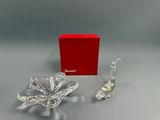 deux figurines en verre transparent posées sur une table, accompagnées d'une boîte rouge