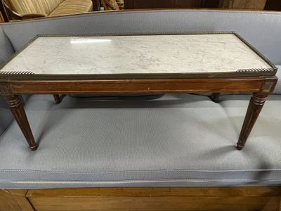 une table basse au plateau en marbre posée devant un canapé bleu