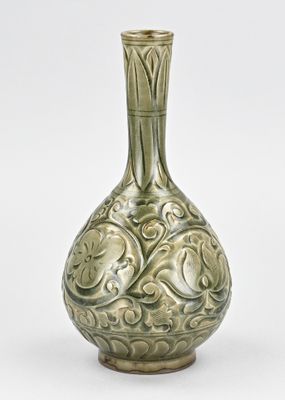 un vase vert posé sur une surface blanche