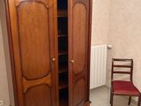 a wooden armoire in the corner of a room with a red chair