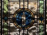 a stained glass window in the corner of a stone wall