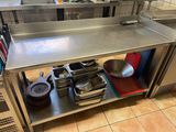 une table en acier inoxydable sur laquelle sont posés des casseroles et des poêles