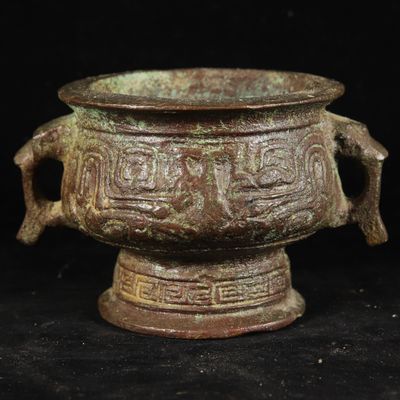 a close up of a bronze vase on a black background