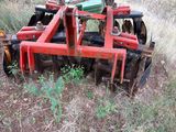 a red plow sitting in the grass next to a tree
