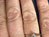 a woman ' s hand with a diamond ring on it