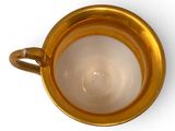a gold cup that is sitting on a white surface