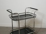 a black and chrome serving cart with two shelves on wheels