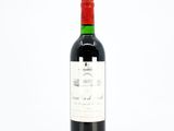 the bottle of red wine is sitting on a white surface