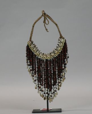 beaded necklace with cowrie and shell beads on a wooden stand