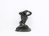 a statue of a woman sitting on a rock with her hands on her head