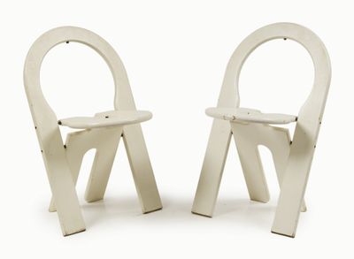 two white chairs sitting next to each other on a white surface