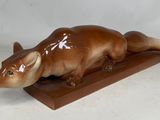 une image représentant une statue de rat posée sur un socle en bois