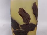 a glass vase with leaves on it on a white surface