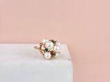 un gros plan d'une bague en or ornée de perles, posée sur un bloc de marbre