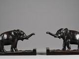 pair of bronze elephants on wooden bases on a gray background