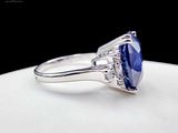 a close up of a blue sapphire and diamond ring on a white surface