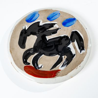 un cheval noir peint sur une assiette blanche à pois bleus