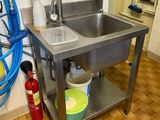 a stainless steel sink in a kitchen with a hose on the wall