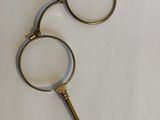 pair of antique brass scissors on a white surface with a magnifying glass