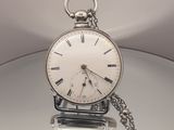 une montre de poche en argent avec une clé, posée sur une table