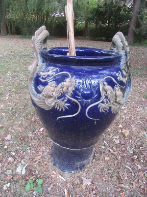 un vase bleu orné de deux oiseaux, posé dans l'herbe