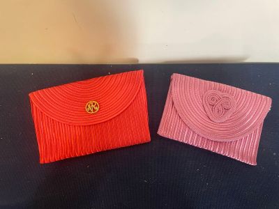 two red and pink clutches sitting on top of a black table