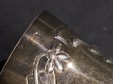 a silver vase with flowers on it sitting on a table