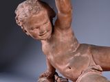 statue of a boy laying on a rock with a bird in his hand