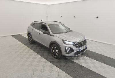 Le SUV argenté est garé dans une pièce blanche dont le sol est en damier noir et blanc.