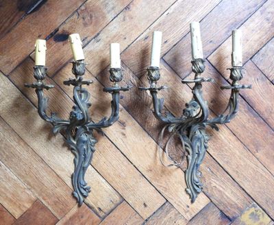 three antique wall sconces with candles on a wooden floor