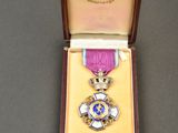 une photo d'une médaille violette et dorée dans un coffret en bois
