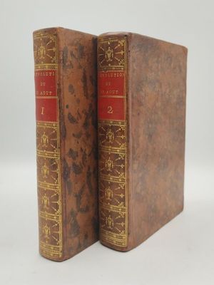 un vieux livre à la couverture rouge posé sur une surface blanche