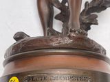 statue en bronze représentant un homme tenant un poisson, posée sur un socle en bois