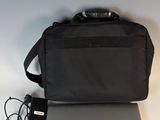 un ordinateur portable Dell avec son chargeur et sa sacoche, posé sur une table blanche