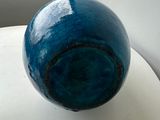 a blue vase sitting on a white table next to a window