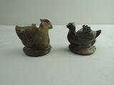two small figurines of birds on a white surface