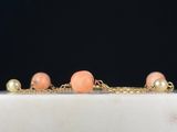 a close up of a gold chain bracelet with peach beads