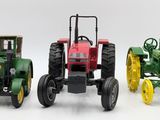 three toy tractors sitting side by side on a white surface