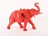 un petit éléphant rouge avec une selle sur le dos