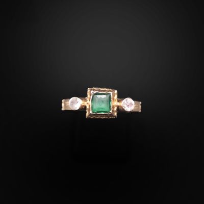 une bague sertie d'une émeraude et d'une perle sur fond noir