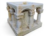 a small stone structure with columns and carvings on it
